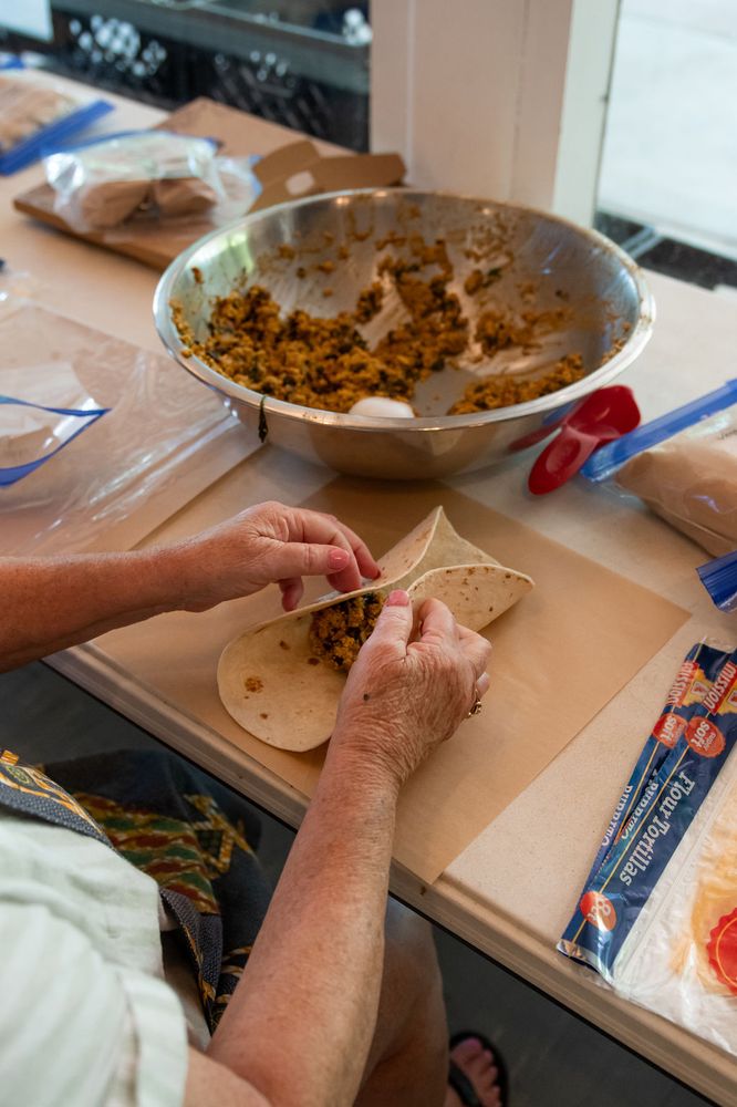 Hands filling tortillas from a big bowl of filling