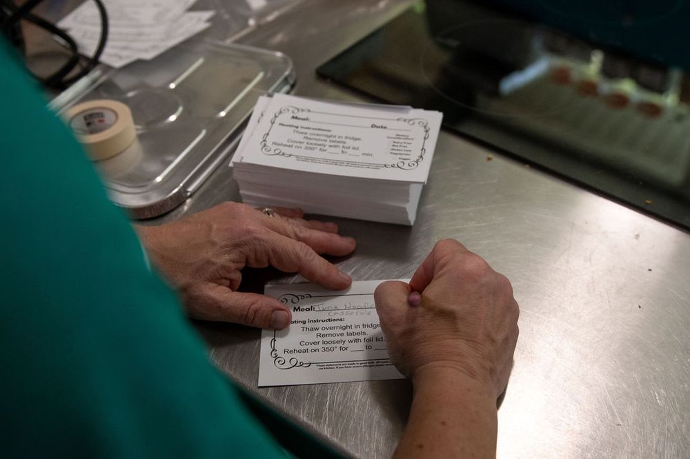 Carrying stacks of finished, labeled meals